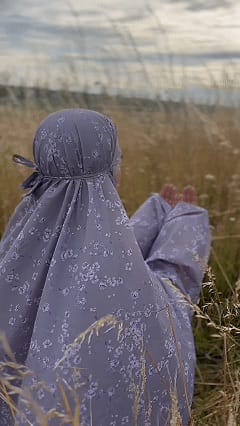 Femme musulmane priant avec une tenue de prière portable dans un espace calme à l'extérieur